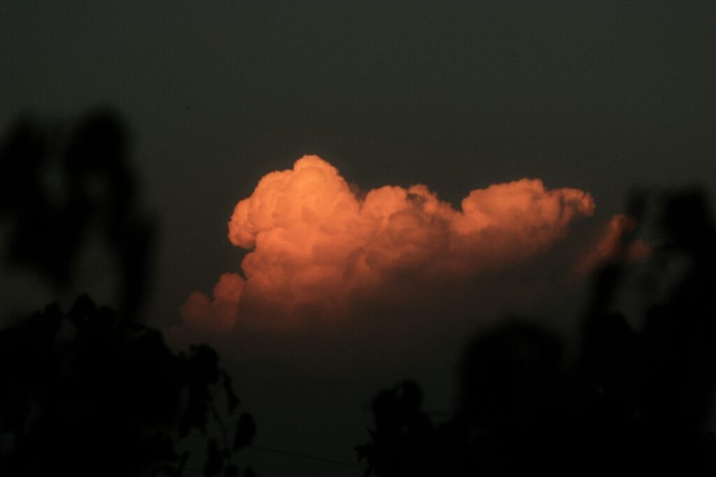 A single orange cloud illuminated by low sun against a dark sky